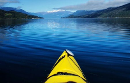 The tip of a yellow kayak on the serene water of the Reloncavi Fjord near Puerto Varas, Chile