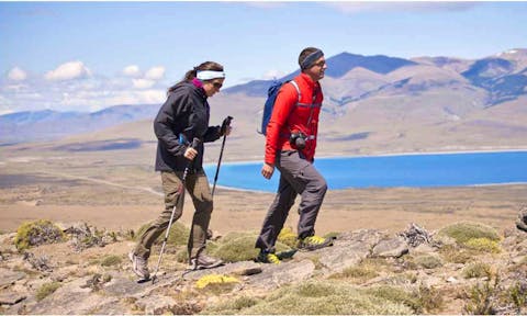 Two hikers in Torres del Paine National Park with a turquiose lake and mountains in the background. Torres del Paine hike, Chile